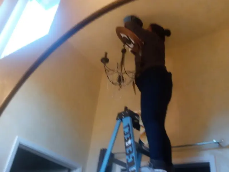 Electrician installing a chandelier in a Layhill residence